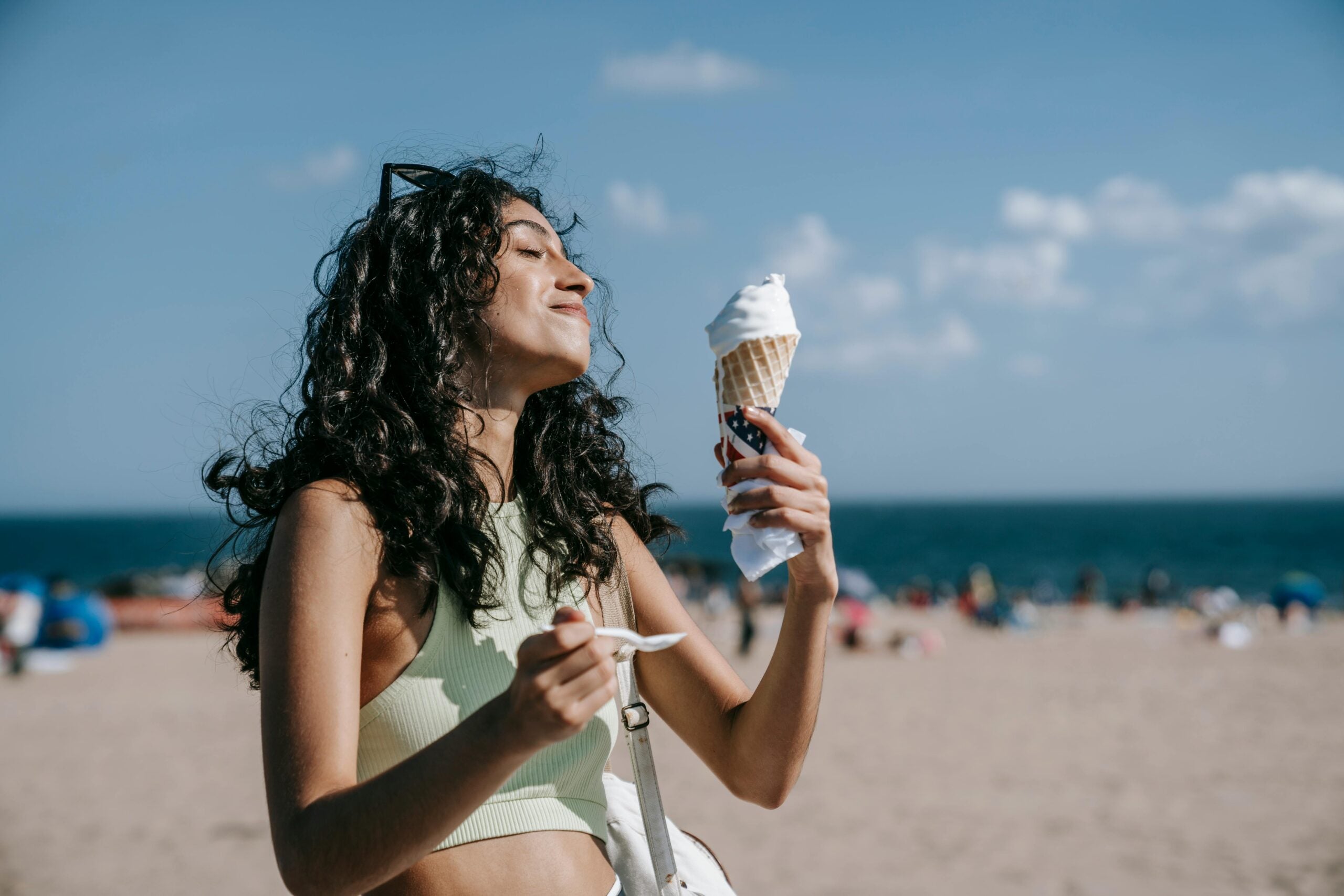 A person enjoys an ice cream cone at the beach