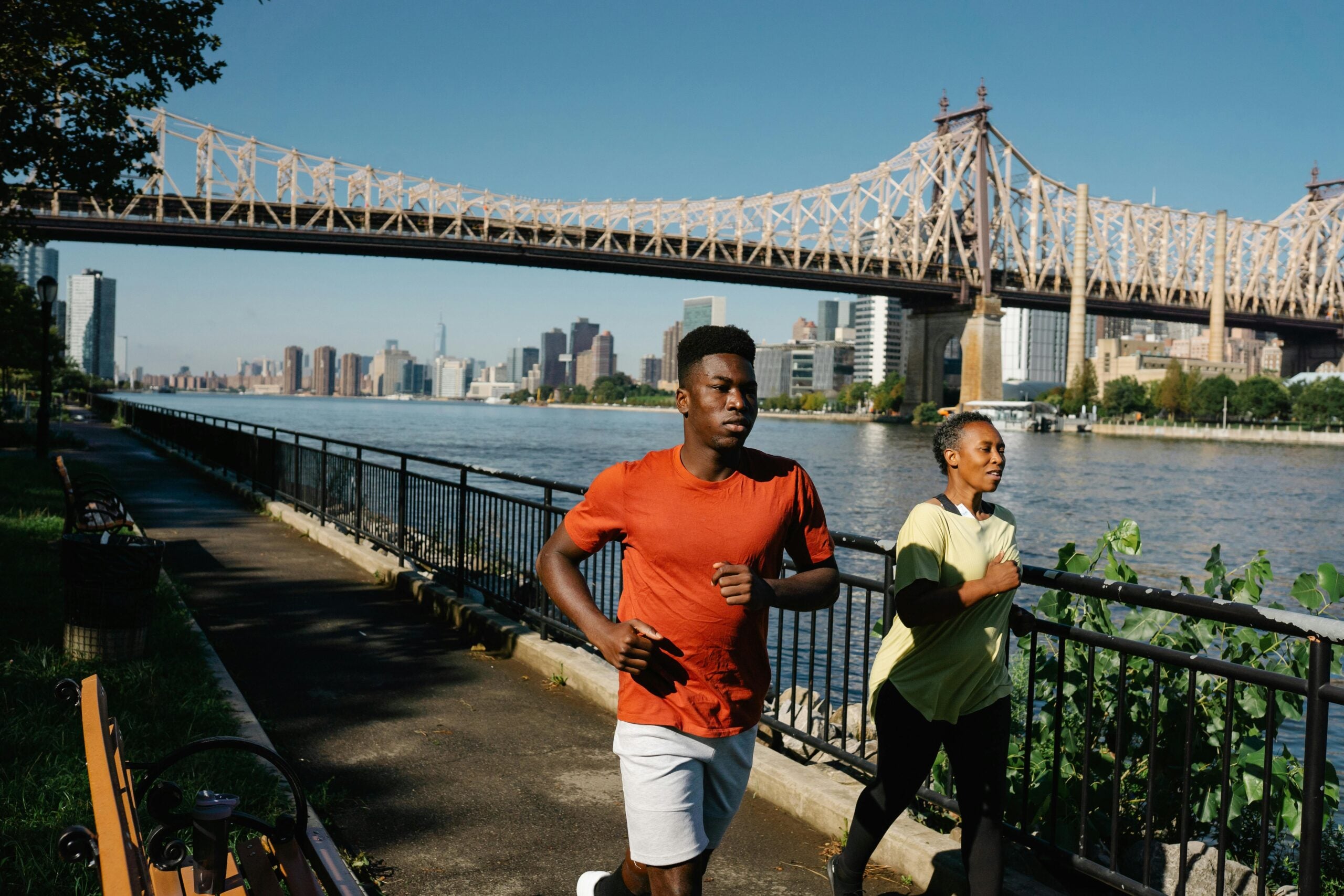 Two people out for a run on a sunny day with a city landscape in the background